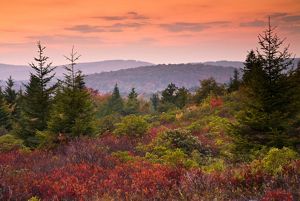 The sun rises over a colorful mountain landscape.