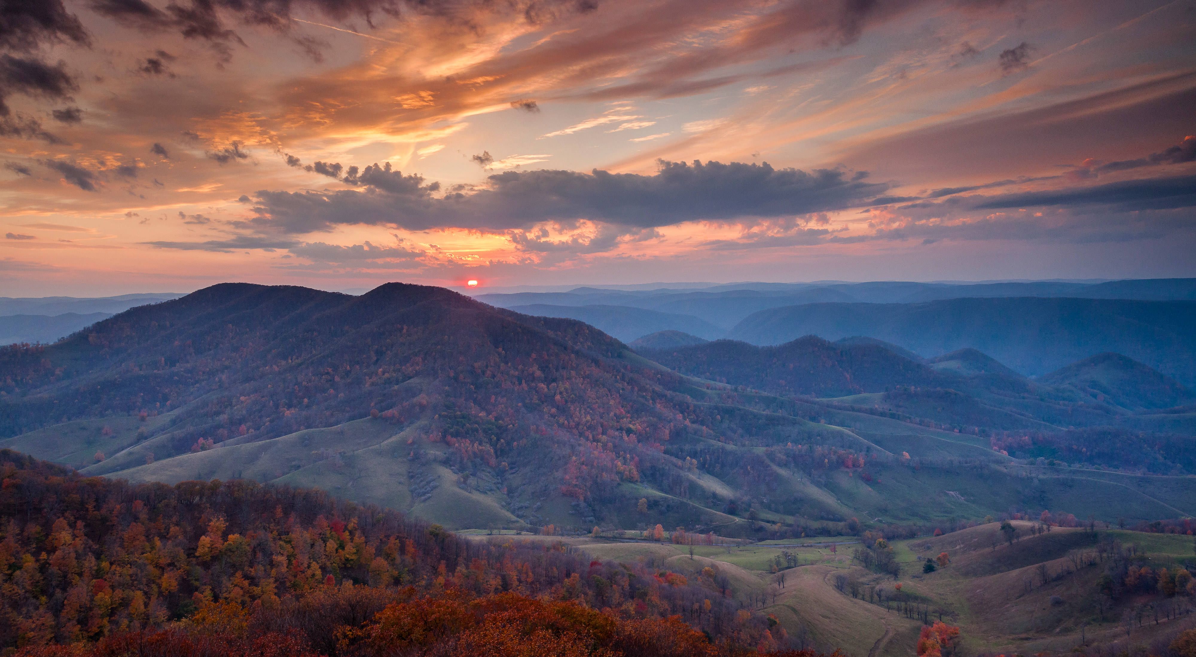Panoramic view of forested mountains at sunset in autumn.