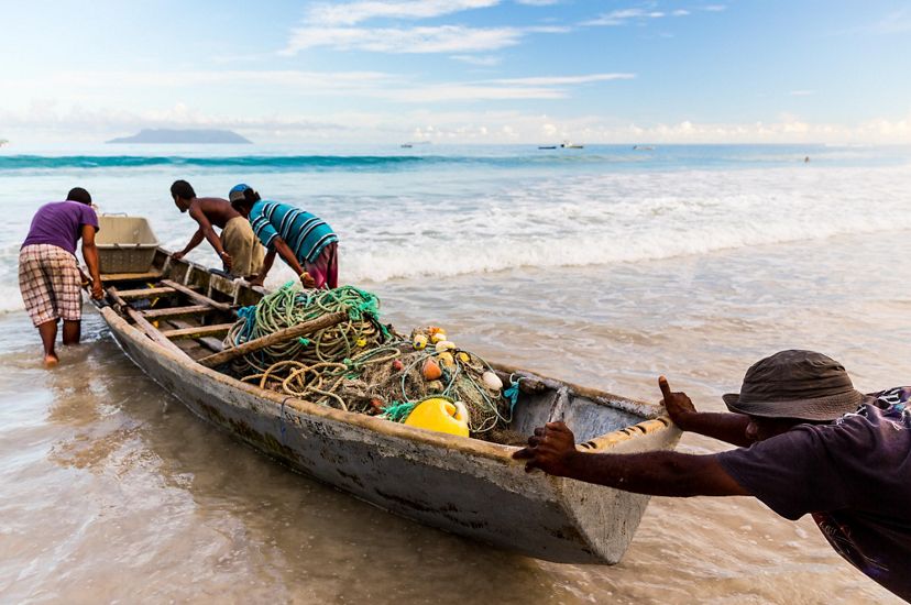 A group of fishers pushing a boat into the ocean