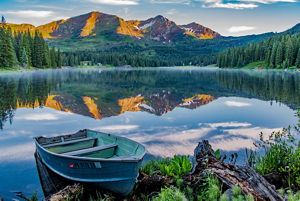 A boat sitting on the shore of a lake.