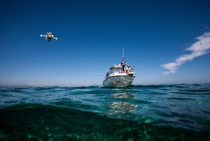 2 people standing on an anchored white power boat.