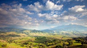 View looking across a vast landscape of green rolling hills and mountains in the distance.