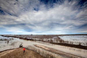 Floodplains stretch out on a wintery day with a boater about to board his little skiff.
