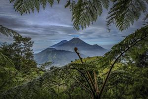 Two mountains in the distance with greenery and valley in the foreground.