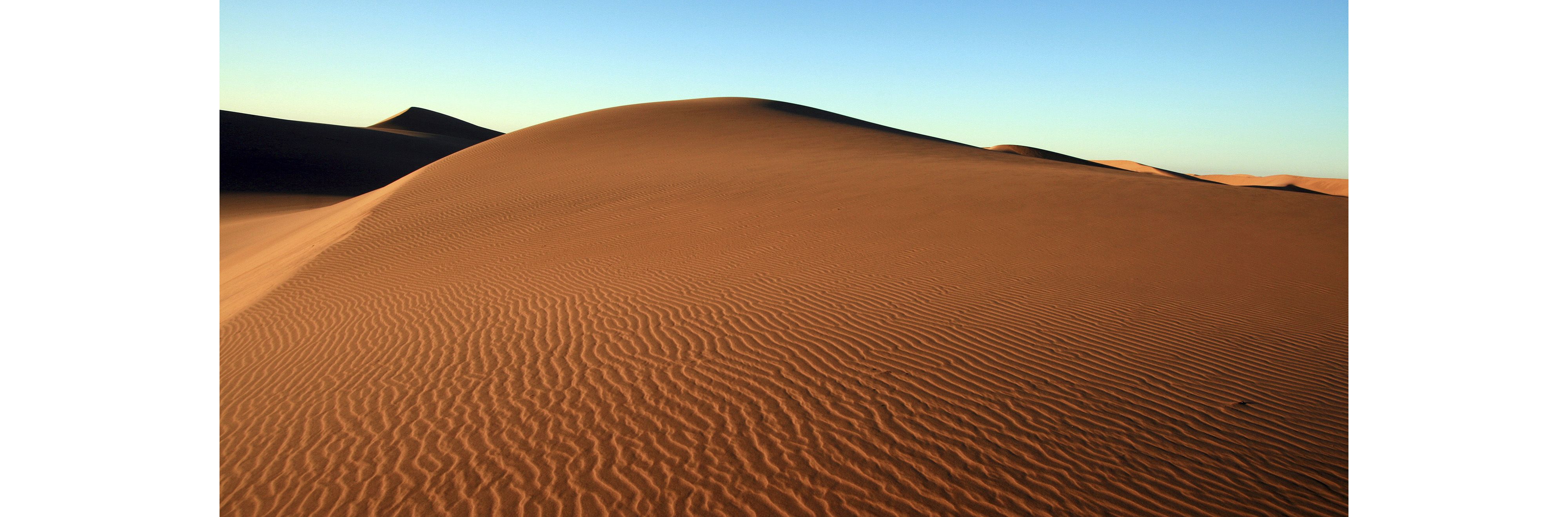 A massive reddish sand dune, with ripples showing trace