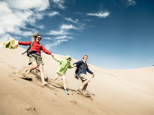 Family running down sand dunes.