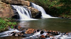 Waterfall cascading into a pond over large rocks.