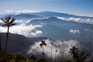 Layers of mountains with white clouds nestled between them.