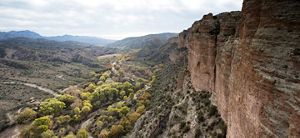 A landscape view of a valley, with steep red canyon wall.