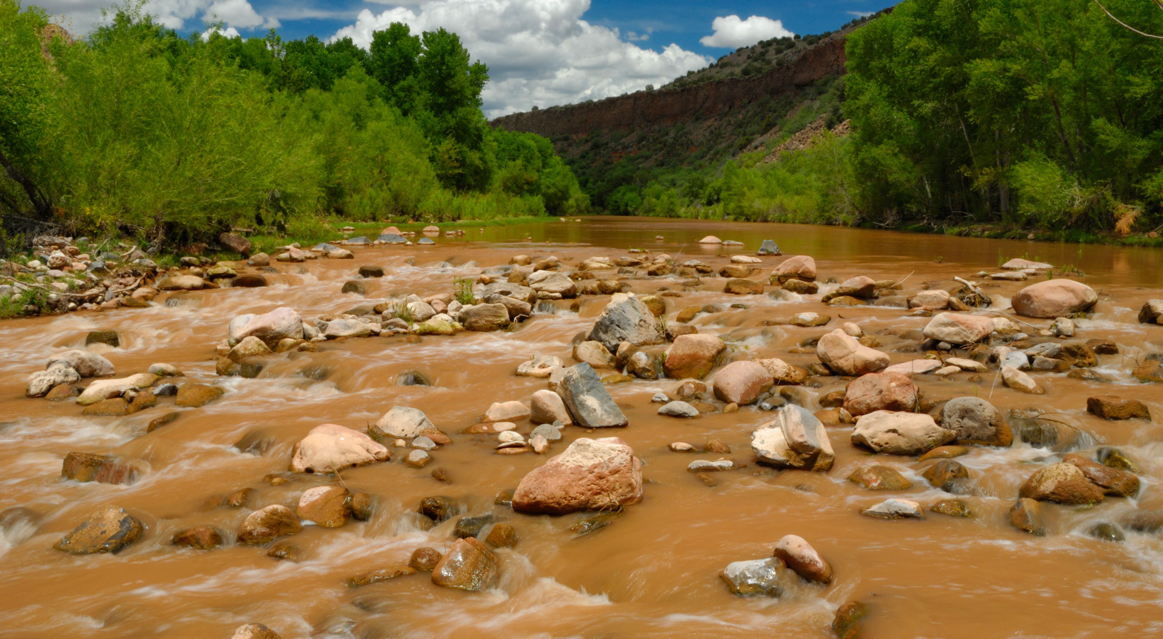 Wide-angle view of a fast-moving, but shallow muddy river.