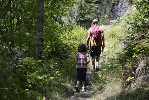 An adult and a child hike through a forest.