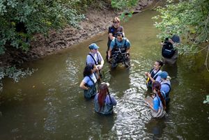 A group of people wading in a river and having a discussion. 