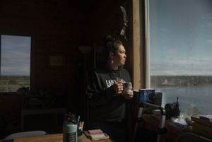 Mary Hostetter drinks a cup of tea in her cabin while she looks out over the river. 
