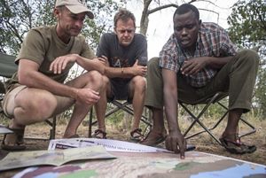 TNC staff and a member of the Ujamaa Community Resource Team (UCRT) look at maps on the ground and discuss their work to help protect the Hadza lands in Tanzania.