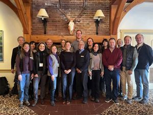 The members of the TNC Vermont Board of Trustees stand together in front of a fireplace and smile for a group photo.