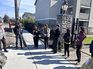 Several people stand on an urban sidewalk and have a discussion.