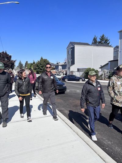 Several people walk down a sidewalk in an urban area.