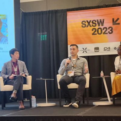 Glenn Ellis Jr. sits in a chair on a stage and speaks into a microphone.