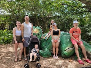 A family stands in front of a dinosaur statue.