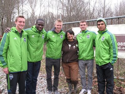 Six people, five in a bright green pullover, pose for a picture with Lylianna.