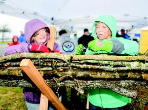 Two women tie large sticks together.