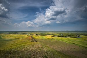  Landscape view from a high vantage point looking across a vast green plain with a long river winding through it.