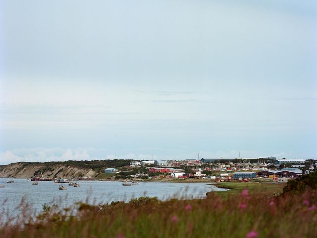 View of houses in a village community positioned along the coastline of a bay. 