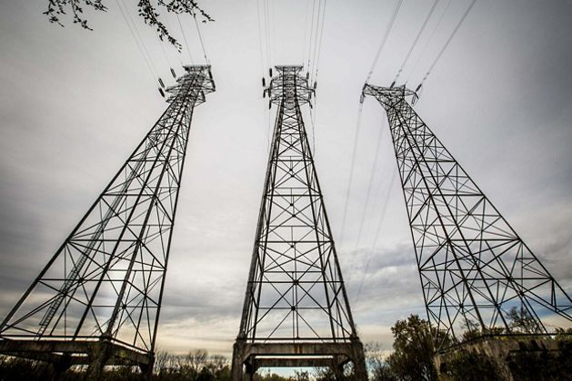 View looking up toward the tops of three electrical transmission towers.