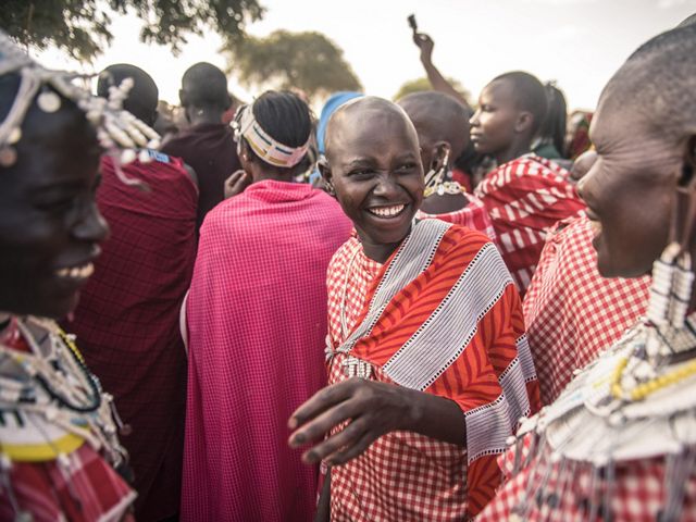 Maasai women watching Maasai men performing traditional dance and chanting during a circumcision ceremony in Tanzania. The Nature Conservancy is working to protect the land that the Hadza people of Tanzania depend upon to maintain their hunter gatherer way of life.