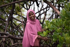 Zulfa Hassan, chair of Mtangawanda Women’s Association, smiles among mangroves.